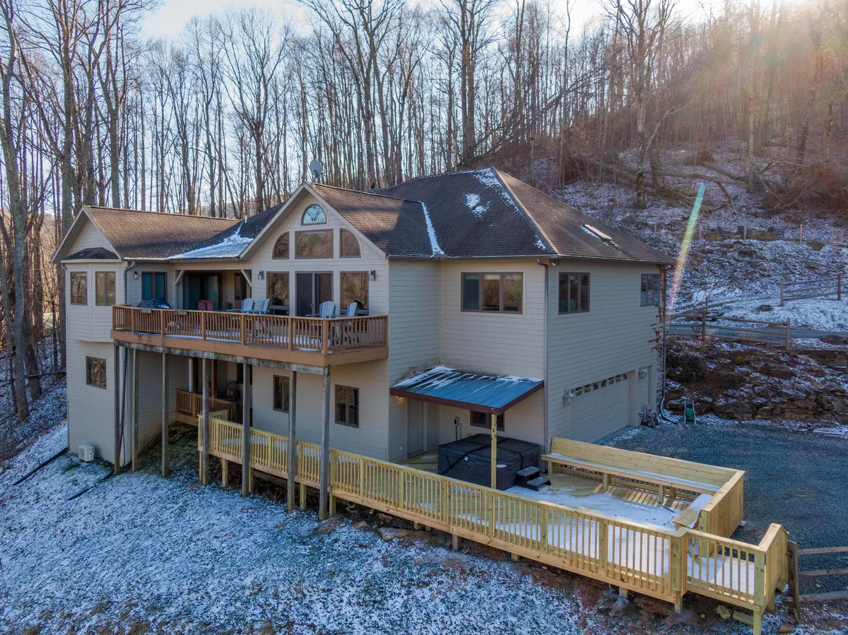 A serene winter exterior shot showing Boulder Sky's expansive deck and balcony with multiple windows, all set against a backdrop of snow-covered ground. The snowy setting invites visions of family gatherings and outdoor relaxation, even during the colder months.